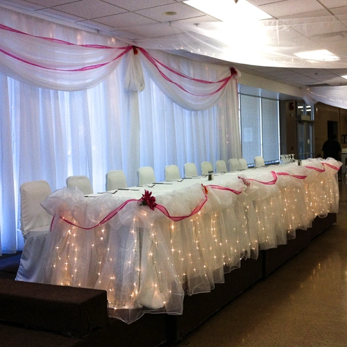 organza backdrop behind head table, lights, burgundy accents