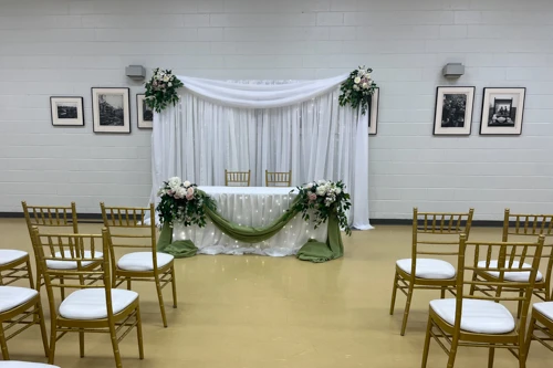 bride and groom table with organza backdrop, green draping and flowers