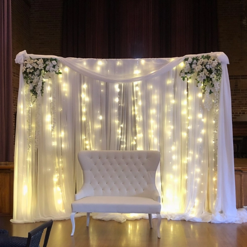 organza backdrop with lights, behind a chair for two