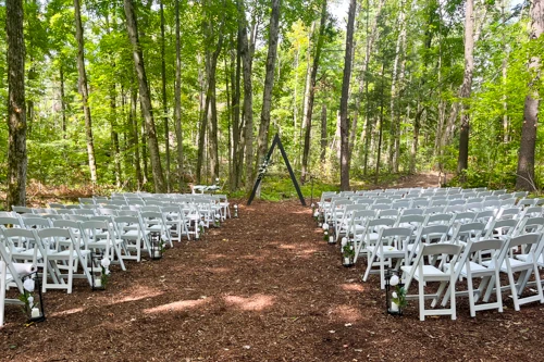 white chairs with padded seats set up in woods for wedding