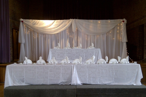 2-tier head table in white linen, and draped organza backdrop with lights
