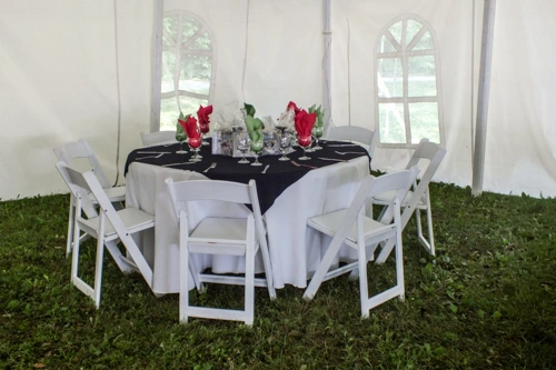 table set up in tent, and white chairs with padded seats