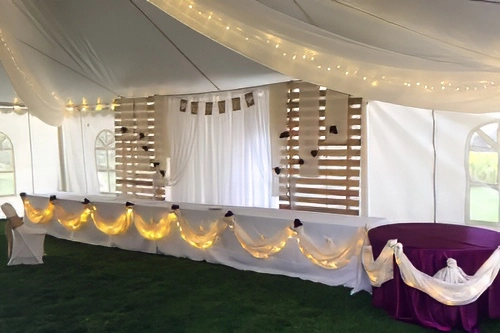 head table in tent with organza decor and lights