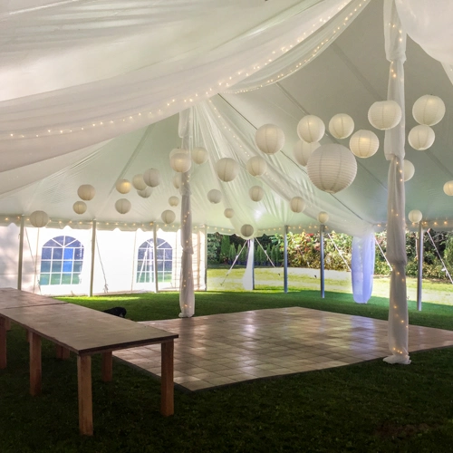 white organza decor with hanging balls, harvest table, and dance floor