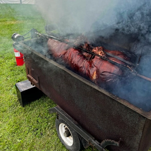 pig roasting on spit in tow-behind barbecue